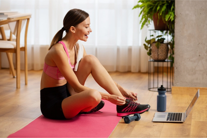 Woman tying shoes before online workout session