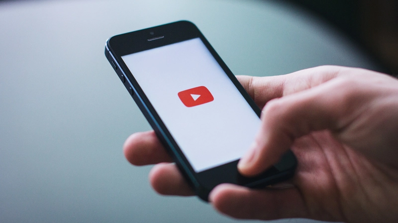 Person holding smartphone with YouTube app on screen